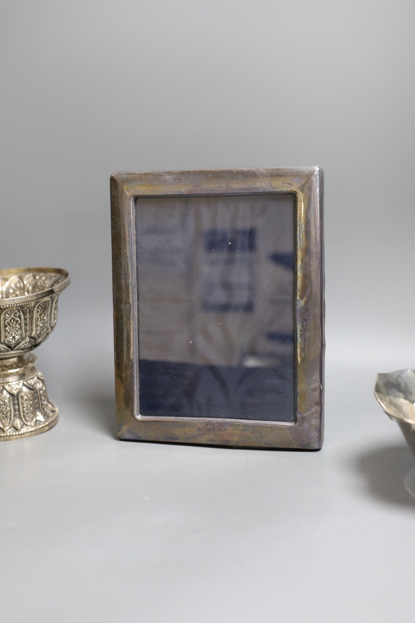 Six assorted embossed Thai white metal bowls, largest 18cm diam., and a silver photograph frame
